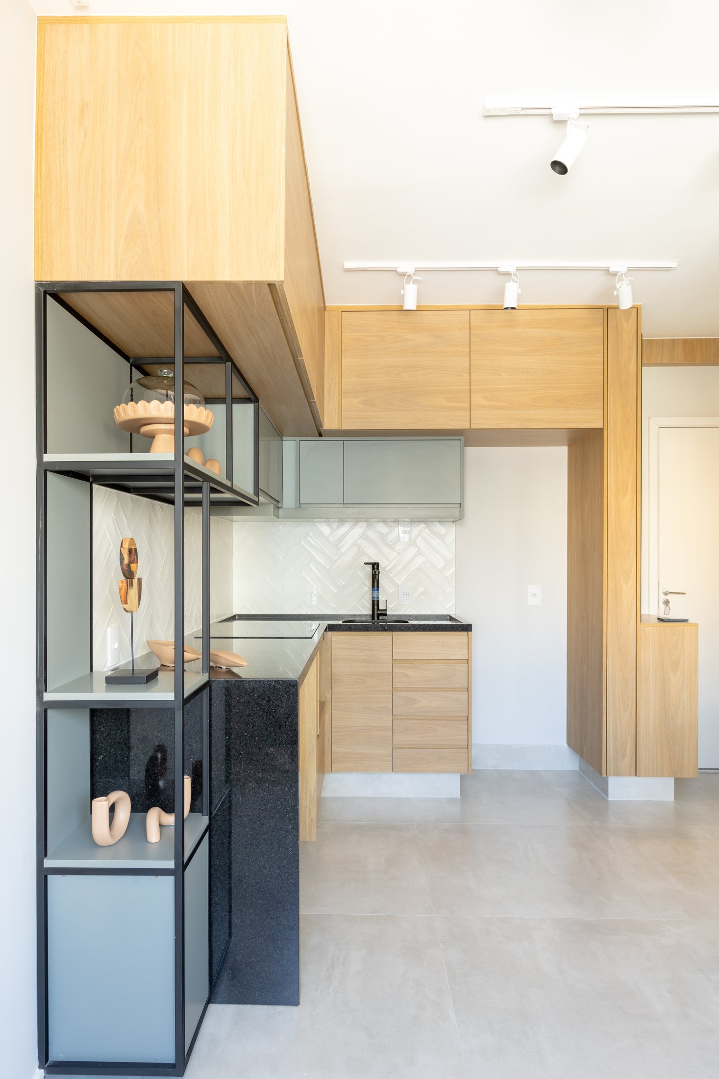 Apartamento compacto com cozinha em marcenaria clara e prateleiras metálicas.